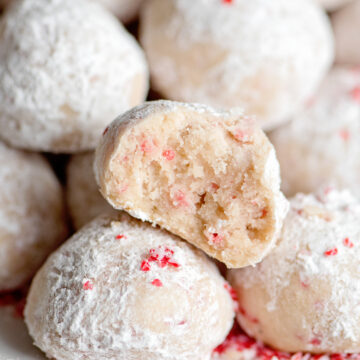 peppermint snow ball cookies on a tray with one cut in half