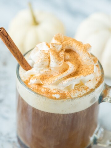 pumpkin spice coffee with whipped cream dusted with cinnamon and cinnamon stick