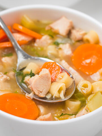 quick and easy chicken noodle soup in a white bowl with a spoon.