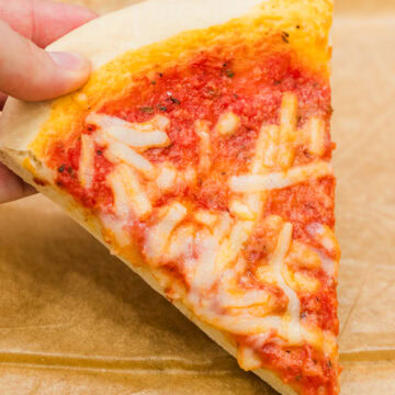 quick pizza dough recipe baked as a plain pie hand holding a slice.