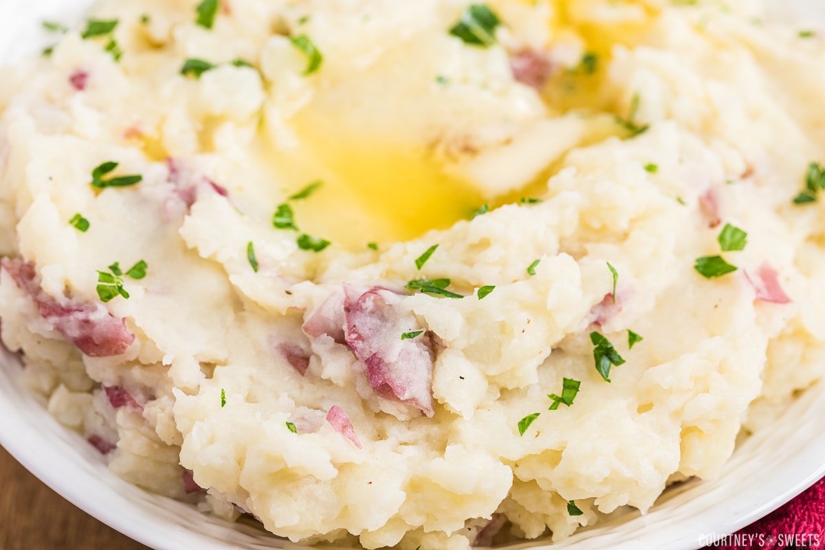 close up of red skin mashed potatoes with melted butter in a bowl.