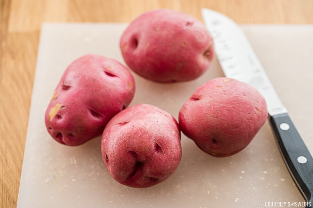 red potatoes on a cutting board with a knife to the right.