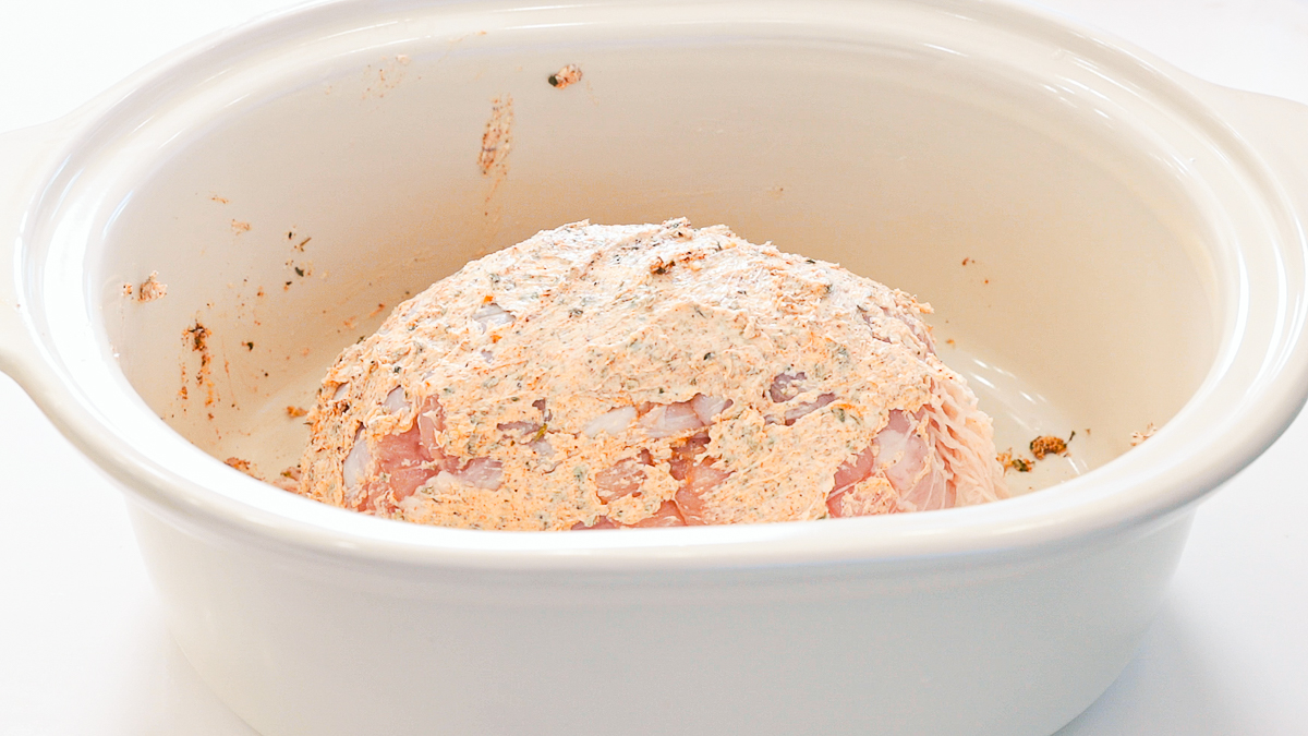 buttered and seasonings mixture on boneless turkey breast in a slow cooker.