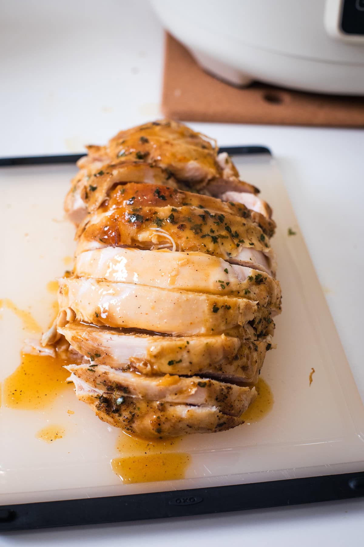 slow cooker boneless turkey breast sliced on a cutting board with gravy on it.