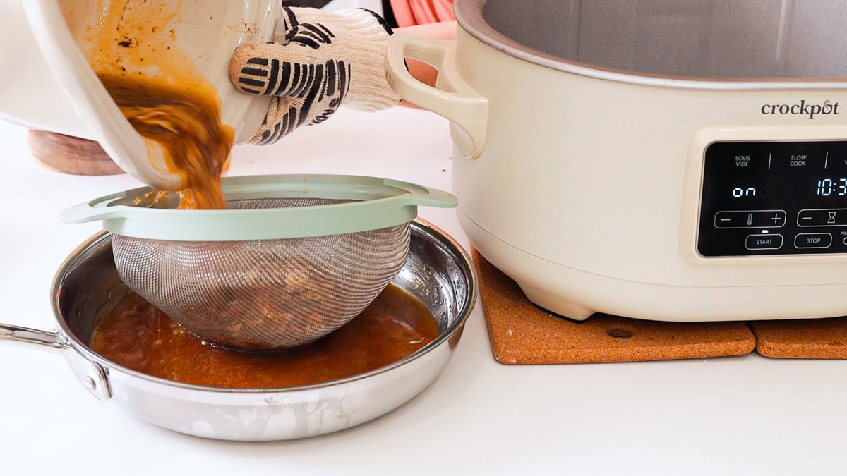 pouring turkey drippings into a mesh strainer.