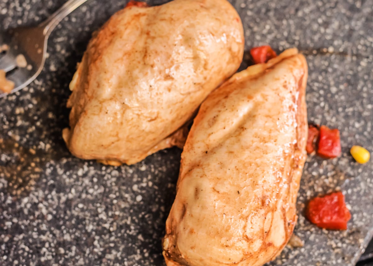 2 slow cooker cooked chicken breasts on a cutting board.