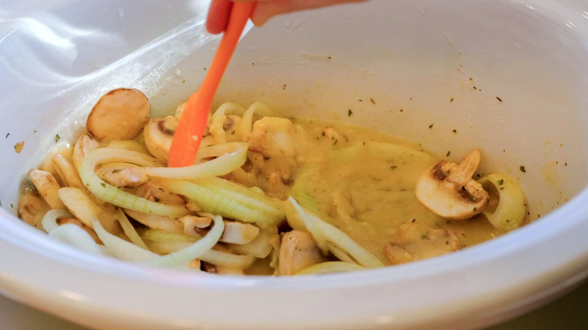 mixing soup mixes, sliced onions, and sliced mushrooms in slow cooker.