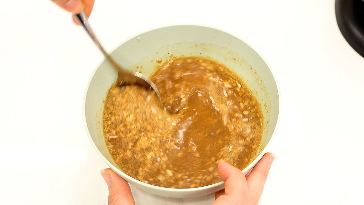 hands mixing flavorful broth in a bowl.