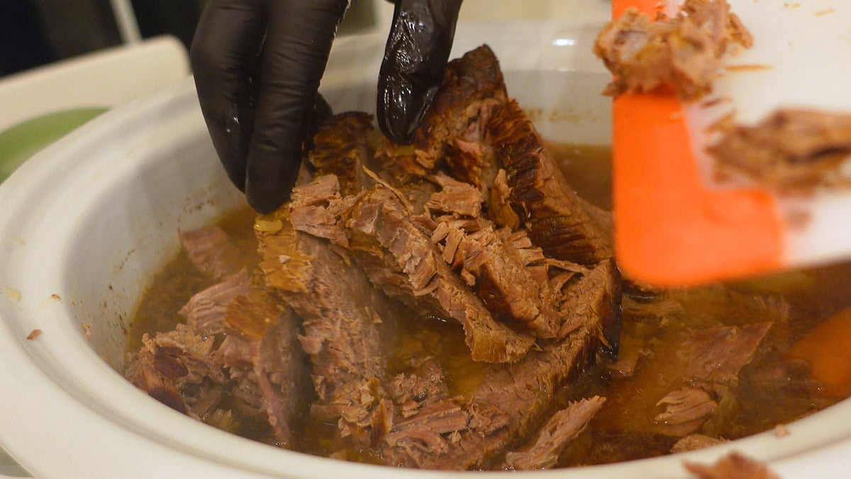 placing sliced roast back into slow cooker.