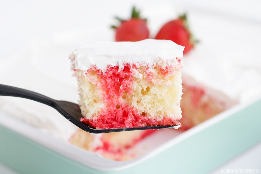 a spatula holding up a piece of strawberry poke cake.