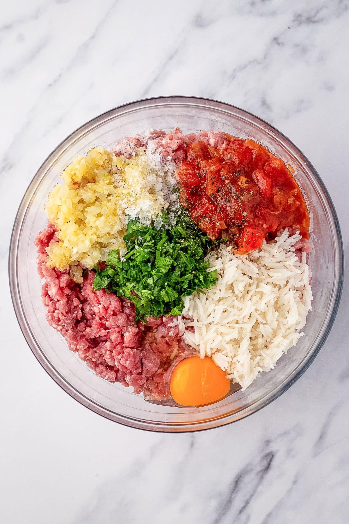 ingredients in glass bowl ready to be mixed for stuffed cabbage roll filling.