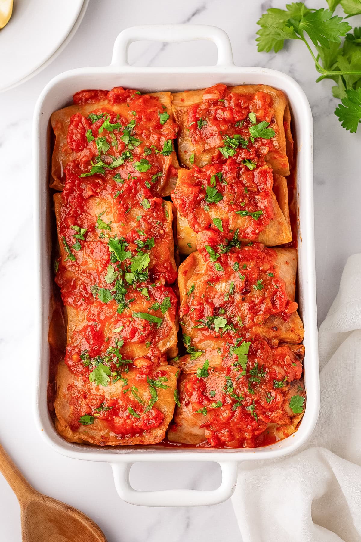 stuffed cabbage rolls in white casserole dish.