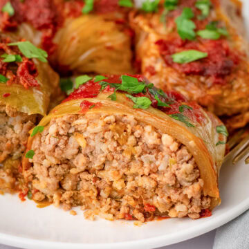 stuffed cabbage rolls on a plate with one cut open.