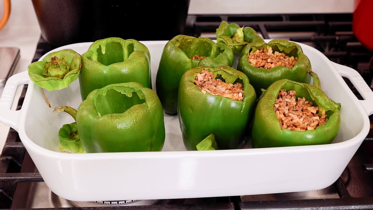 stuffing roasted bell peppers in a casserole dish.