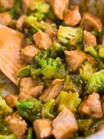 teriyaki pork stir fry with broccoli in a pan with a wooden spatula.