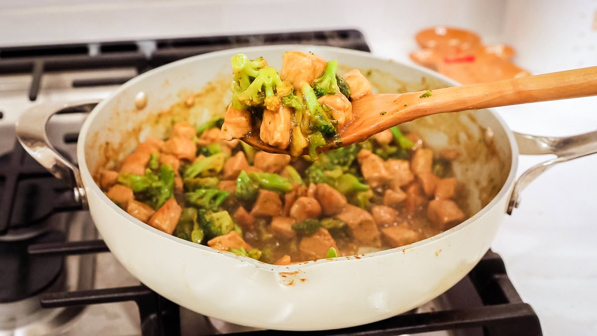 cooked teriyaki pork stir fry with broccoli in a pan with a serving spatula.