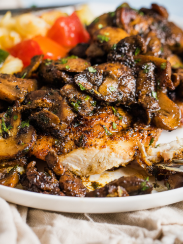 chicken and mushrooms on a plate with a side of vegetarian pasta salad.