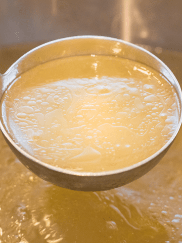 homemade chicken broth on soup ladle in a stockpot.